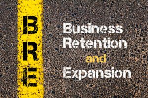 Business Retention Expansion in white lettering on asphalt pavement background. Letters BRE on yellow stripe on pavement background