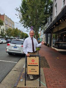 Jeff Small standing on Caroline St in Fredericksburg, VA pointing towards YMMAS