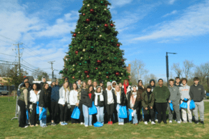 Group of high school students standing in front of a christmas tree.