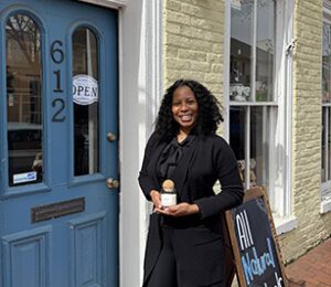 Cherry Riley standing in front of store holding a candle.